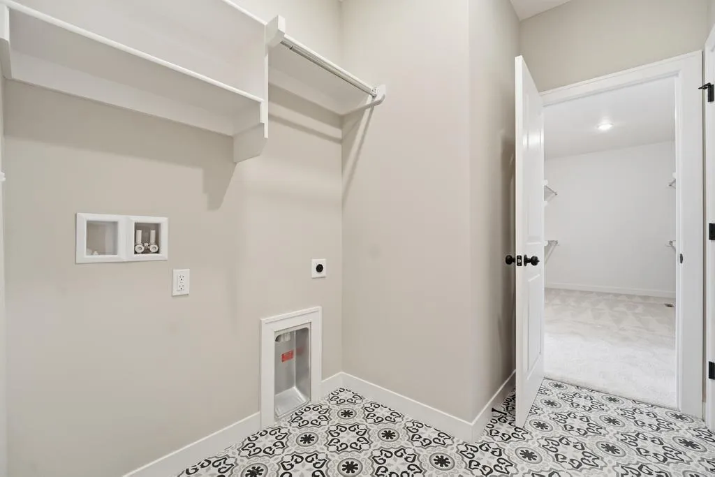 Walk-in closet with white shelving, rod, black and white patterned tile floor, and open door to bedroom beyond.