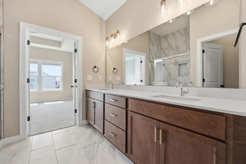 Master bathroom with dual vanity, marble backsplash, large mirrors, and white countertops.