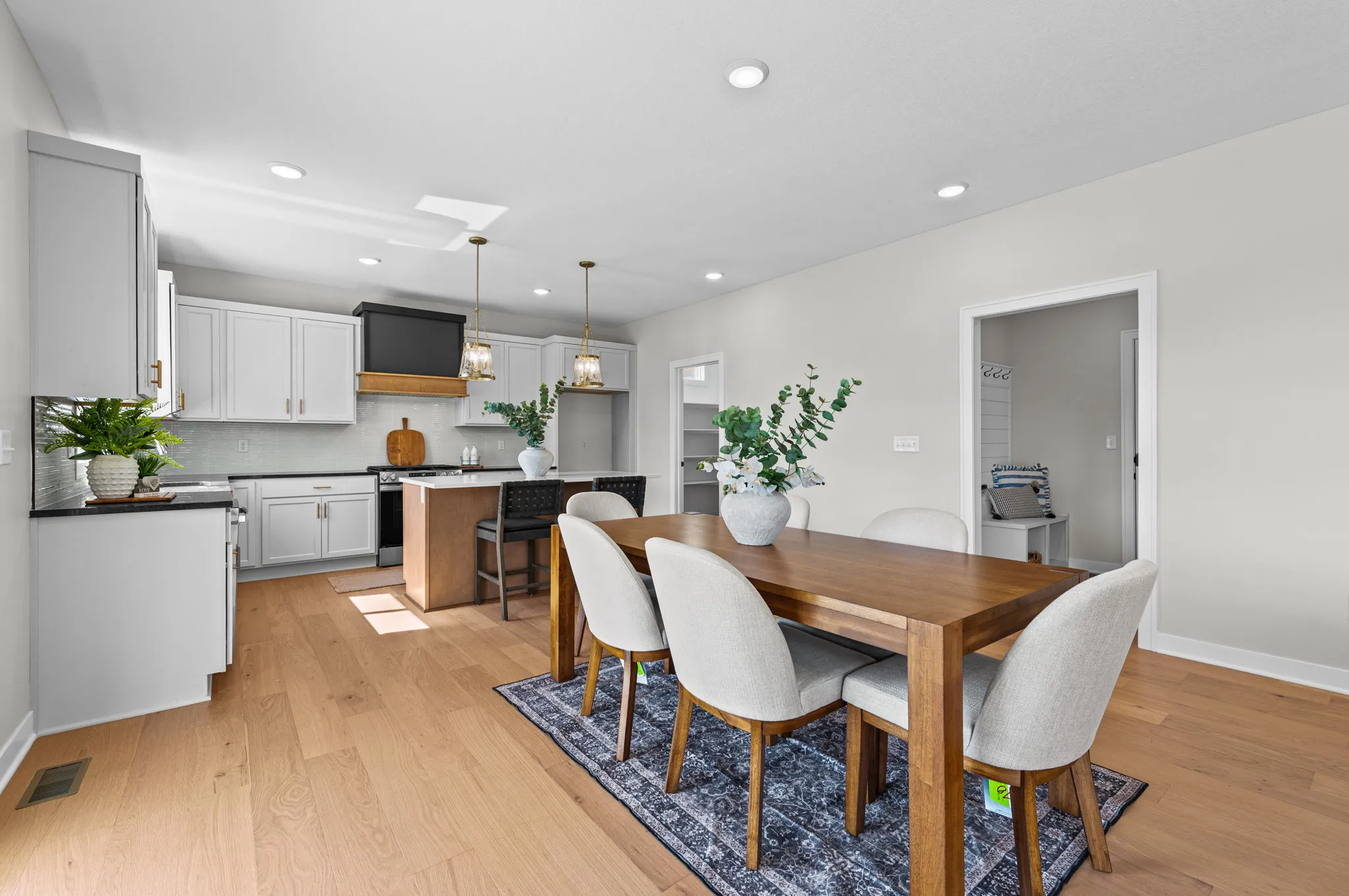 Open kitchen and dining area with white cabinetry, wood dining table, and hardwood flooring throughout.
