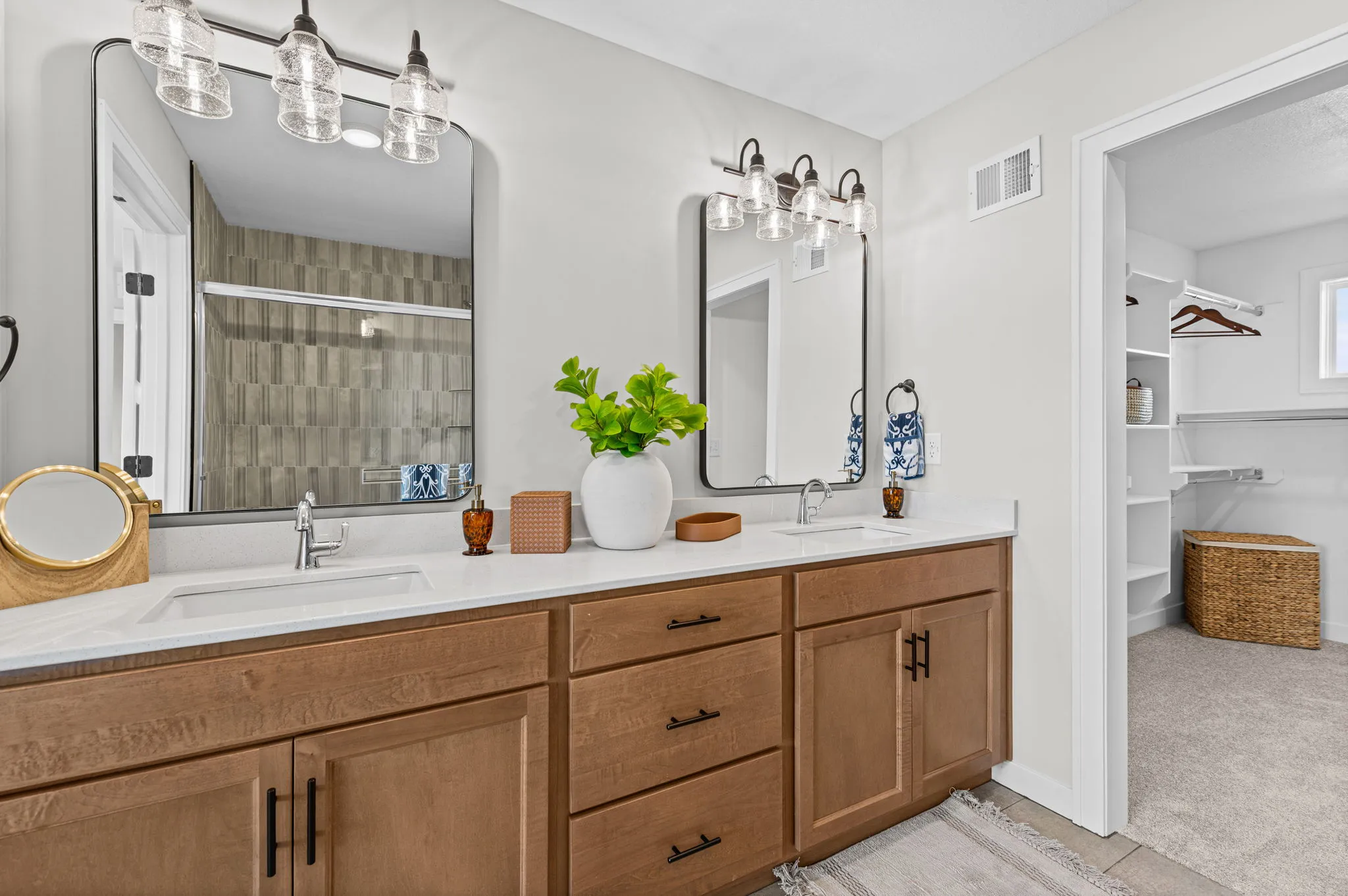Master bathroom with dual vanity, wood cabinetry, white countertop, framed mirrors, and pendant lighting.