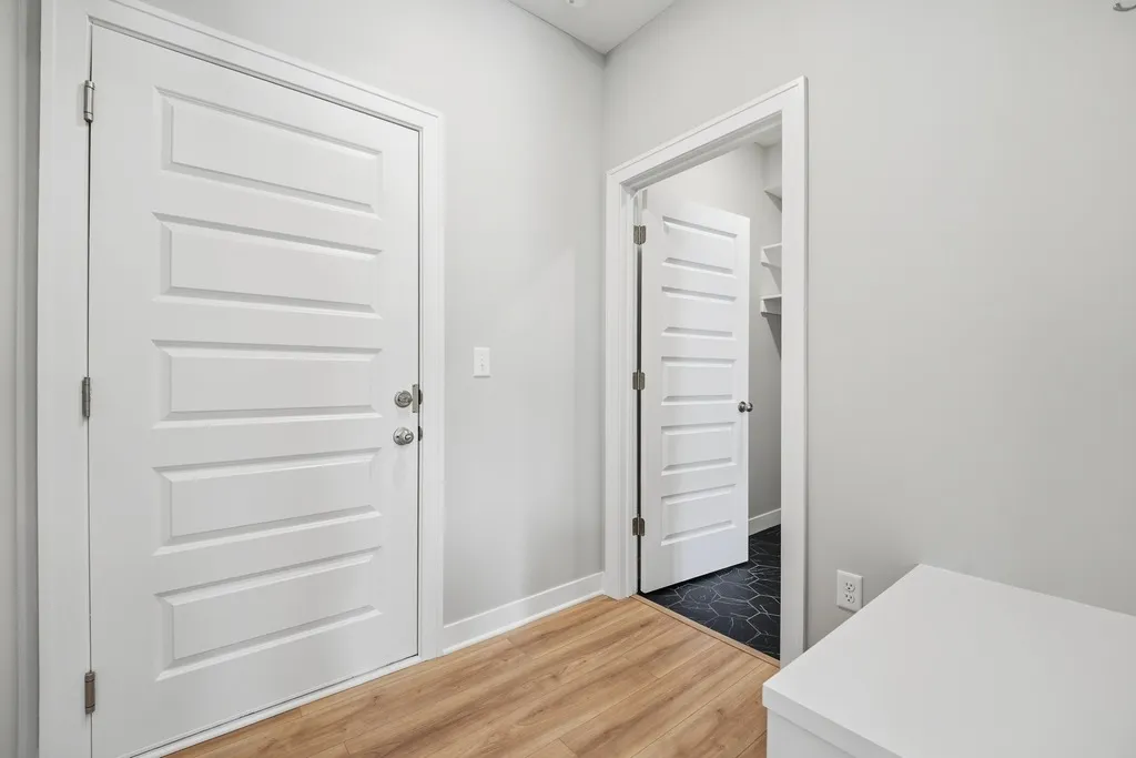 White five-panel interior doors with wood flooring and light gray walls in an entryway.