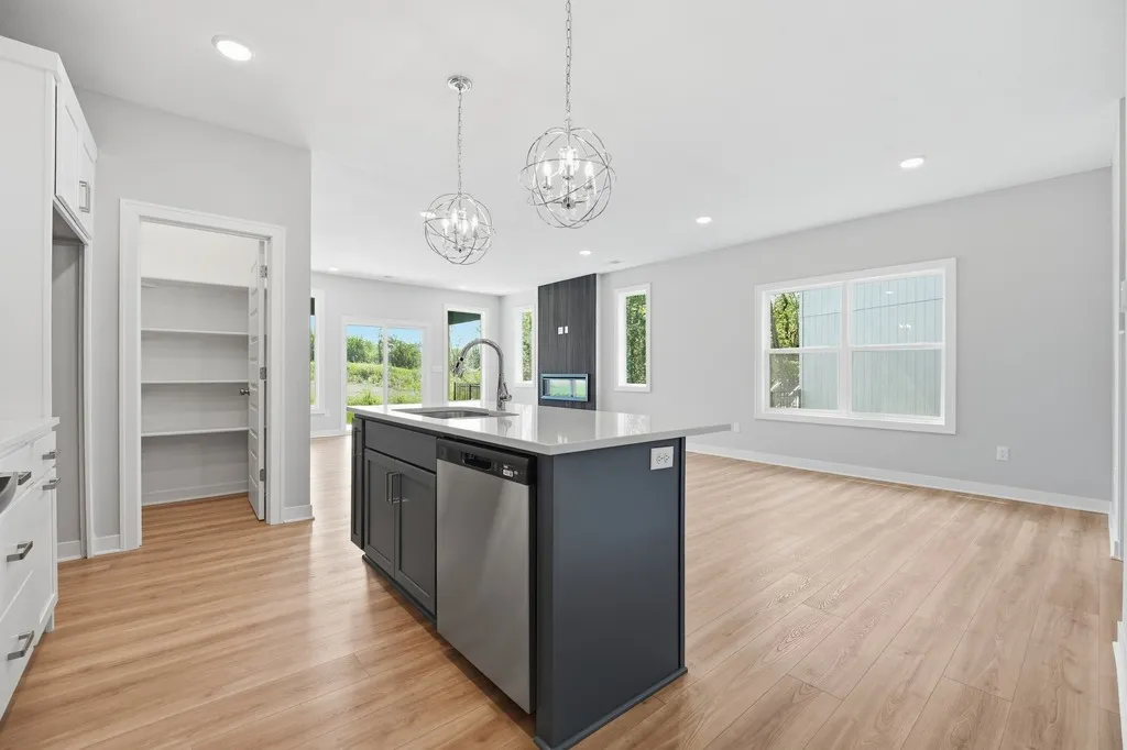 Open kitchen with black island, white cabinetry, spherical pendant lights, and hardwood flooring.
