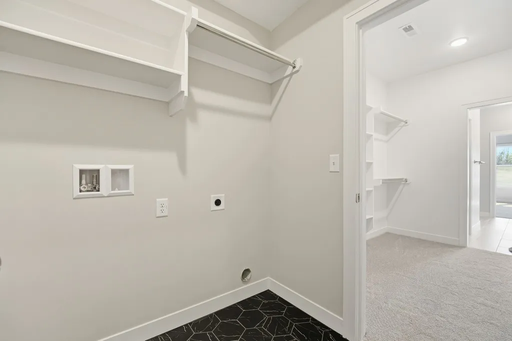 White walk-in closet with shelving, hanging rod, hexagonal tile floor, and built-in organizers.