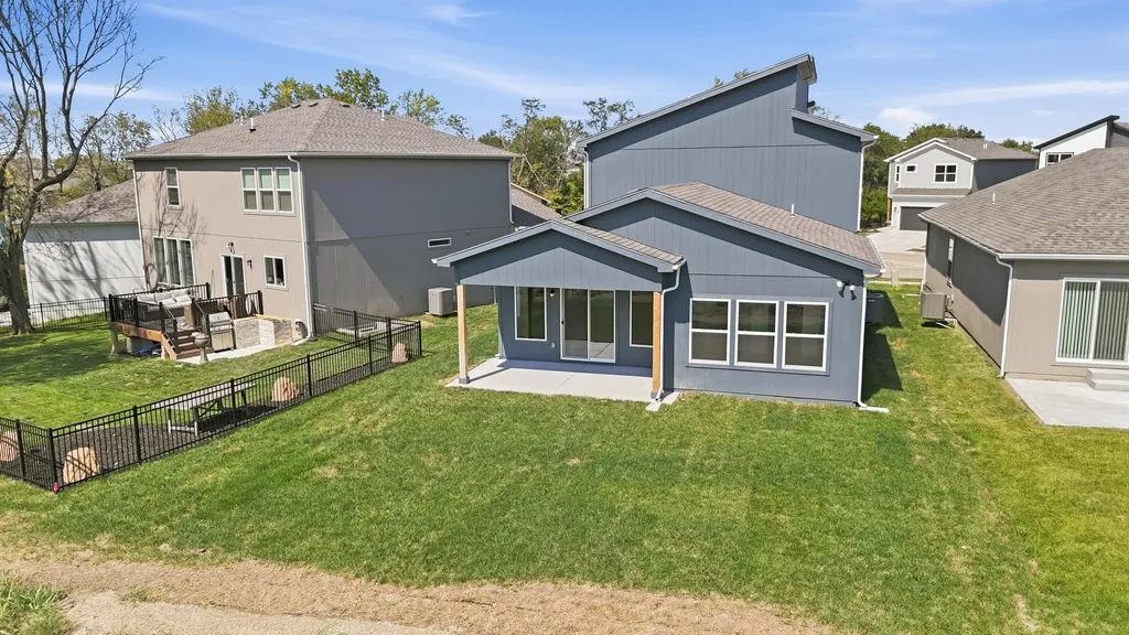 Blue and gray modern home with large windows and covered porch in residential community with neighboring houses and green