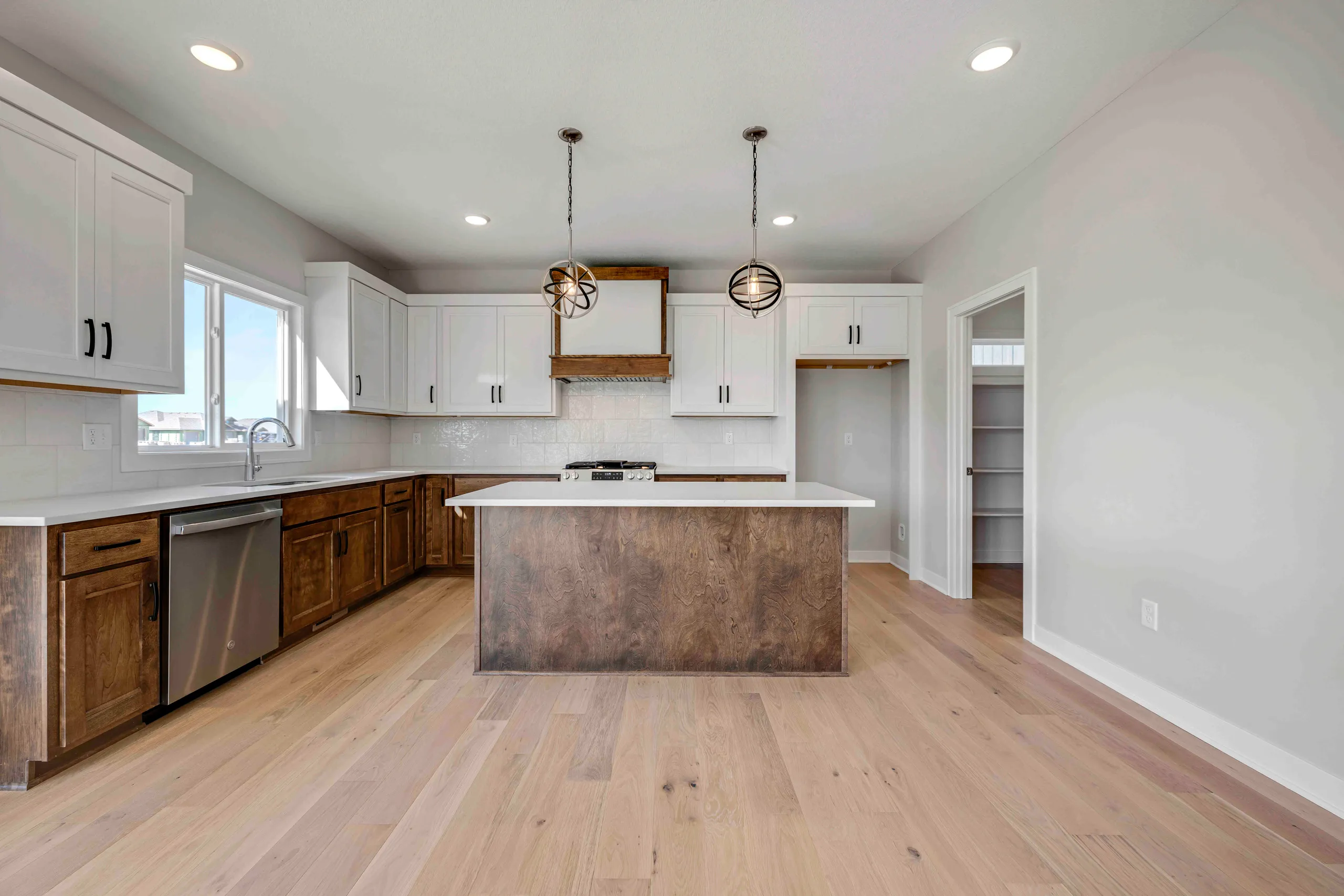 Kitchen with white upper cabinets, dark wood lower cabinets, island with white countertop, stainless steel appliances, and