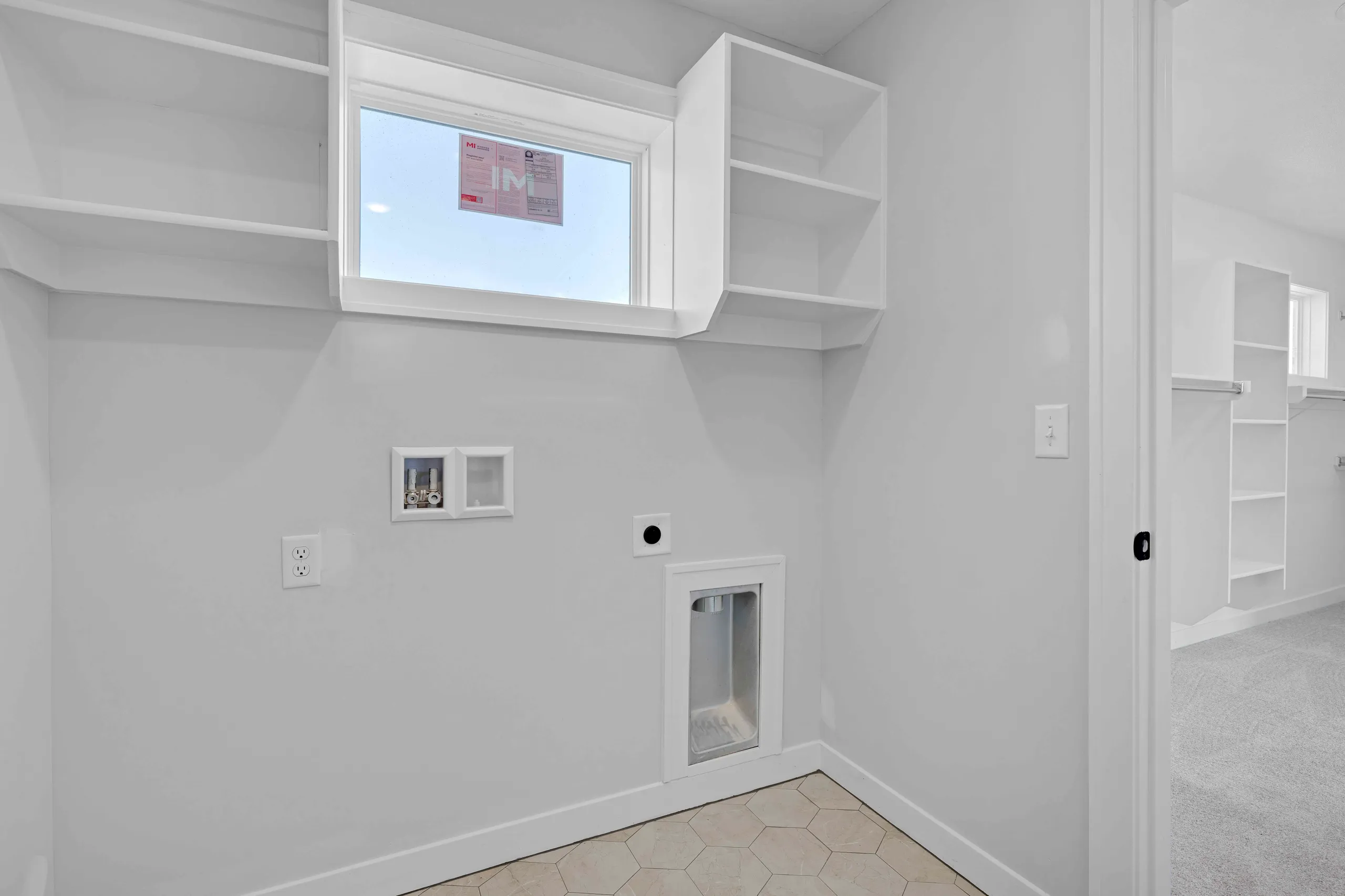 White pantry with window, shelving, refrigerator, and hexagonal tile flooring.