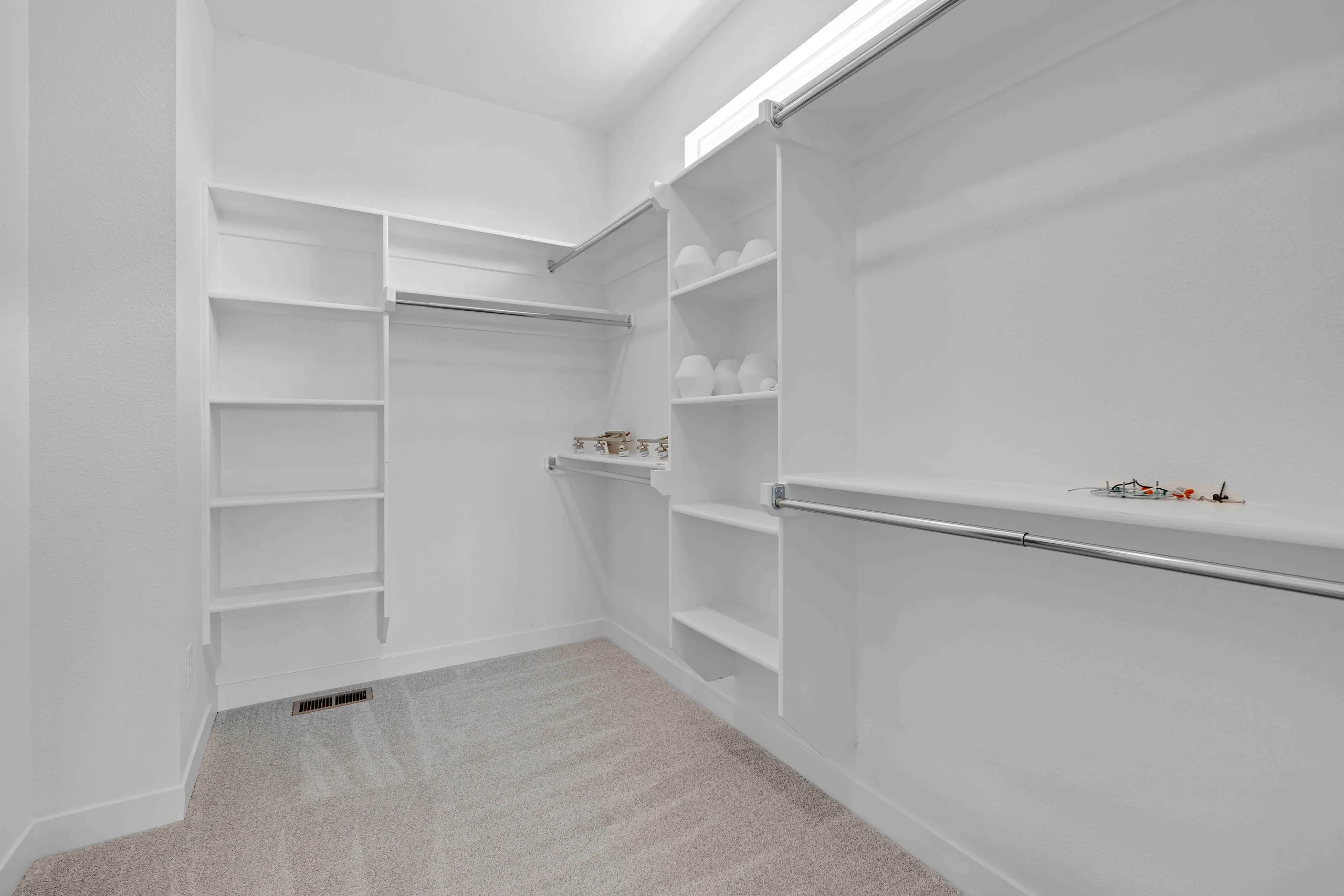 Walk-in closet with white shelving, hanging rod, and carpet flooring.