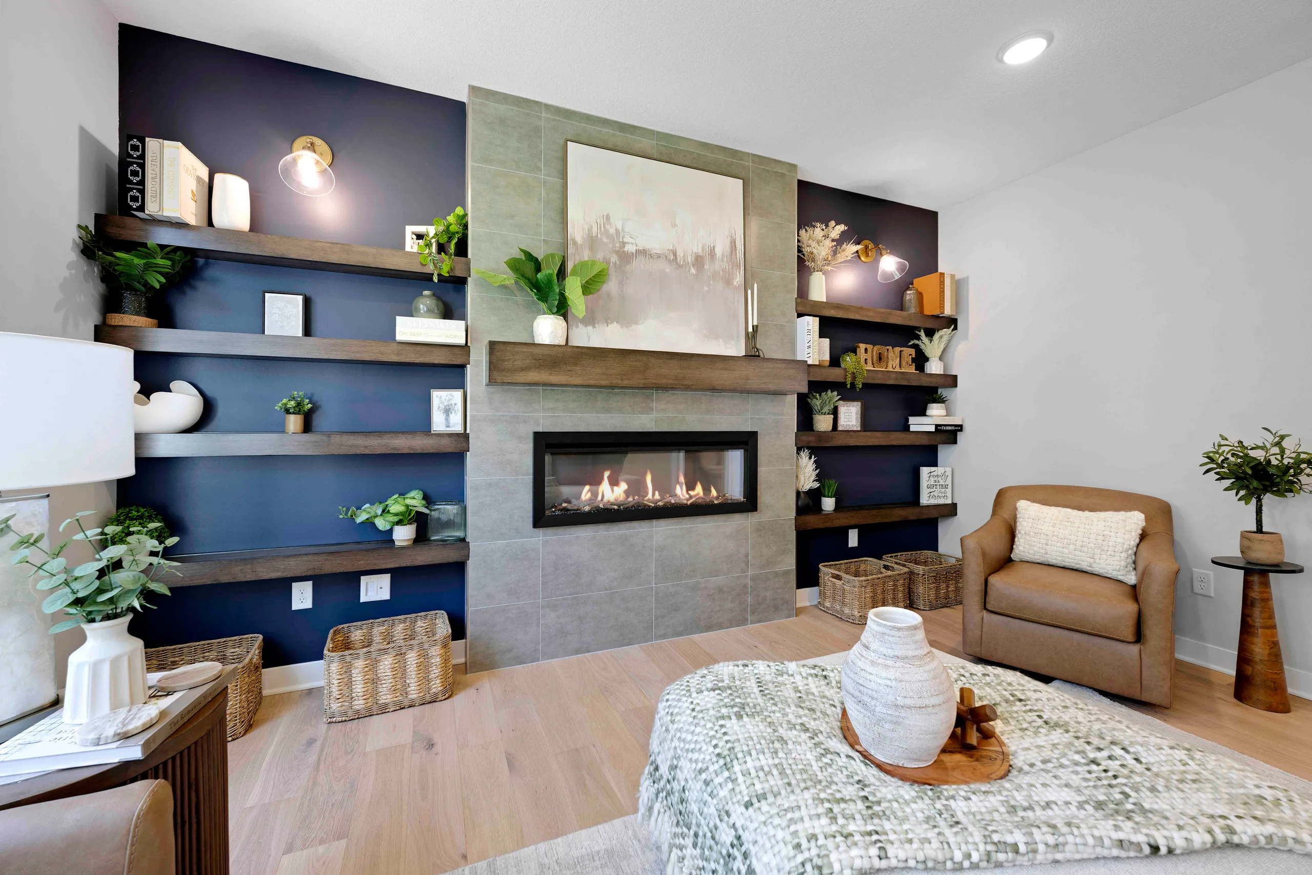 Living room with blue accent wall, wood shelving, fireplace, tan armchair, and wood flooring.